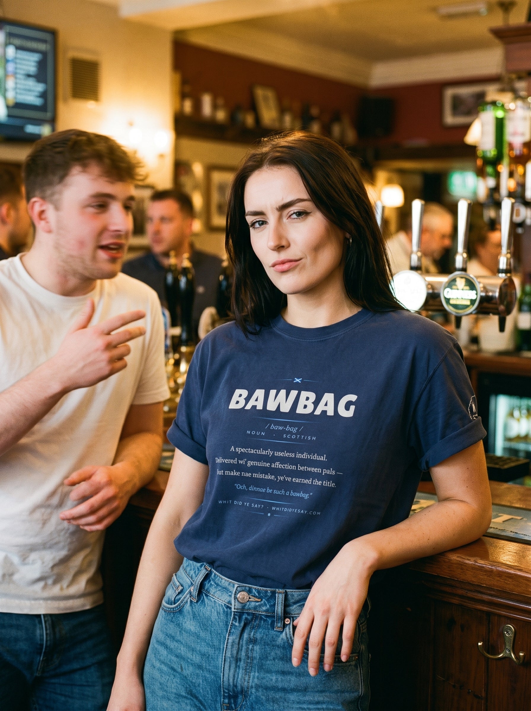 Woman in a pub wearing the navy BAWBAG dictionary definition tee