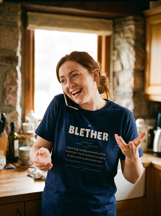 Woman on the phone in a kitchen wearing the navy BLETHER dictionary definition tee